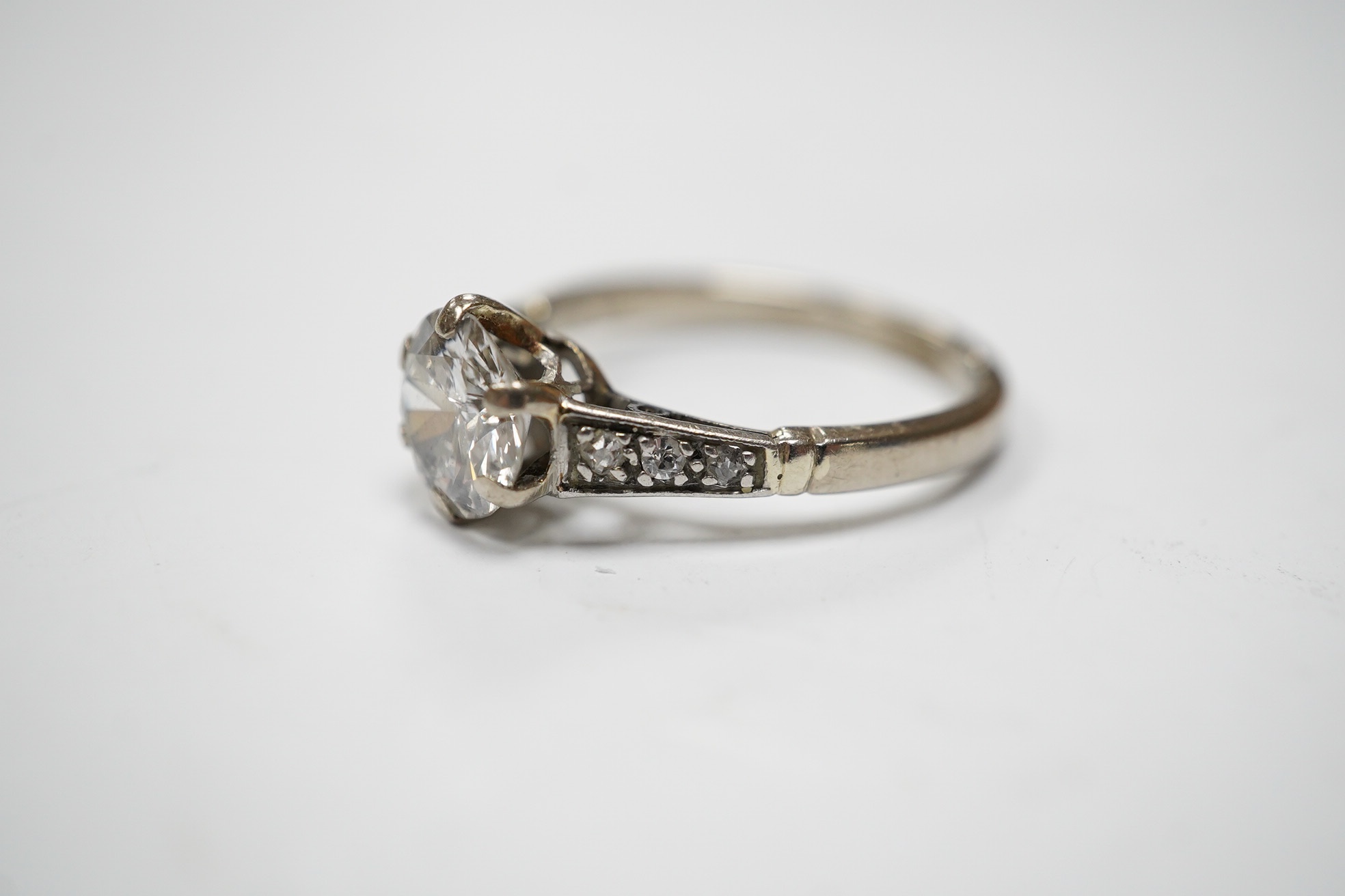 A white metal (stamped 18ct) and single stone diamond set ring, with six stone diamond set shoulders, the central stone weighing approximately 1.10ct, size M, gross weight 3.7 grams. Condition - poor to fair.